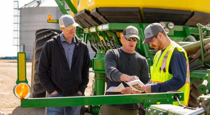Three men talking near farm equipment