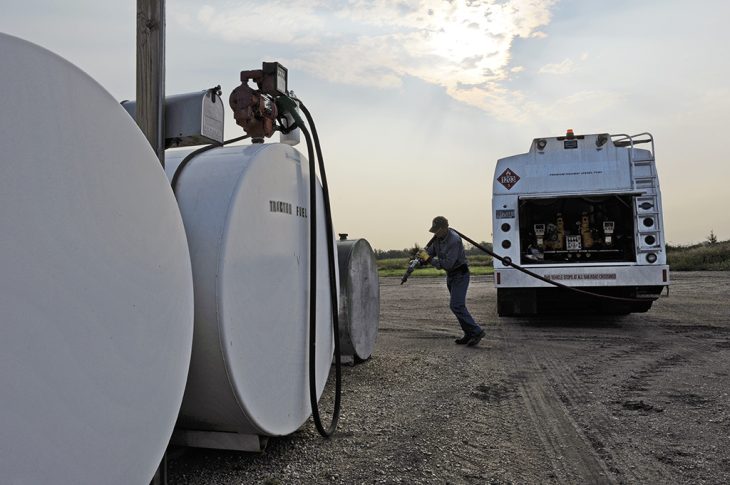 Man pulling line from a propane truck to a tank for a refill