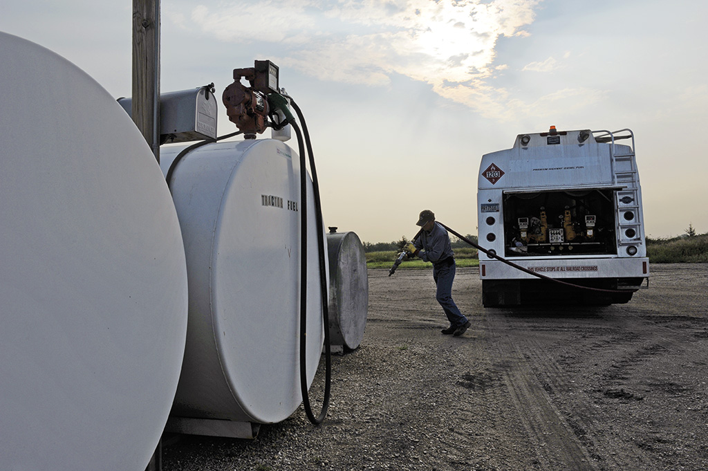 Man pulling line from a propane truck to a tank for a refill