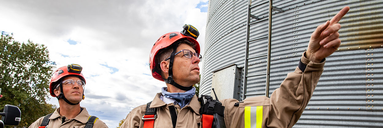 Firefights standing beside a grain bin